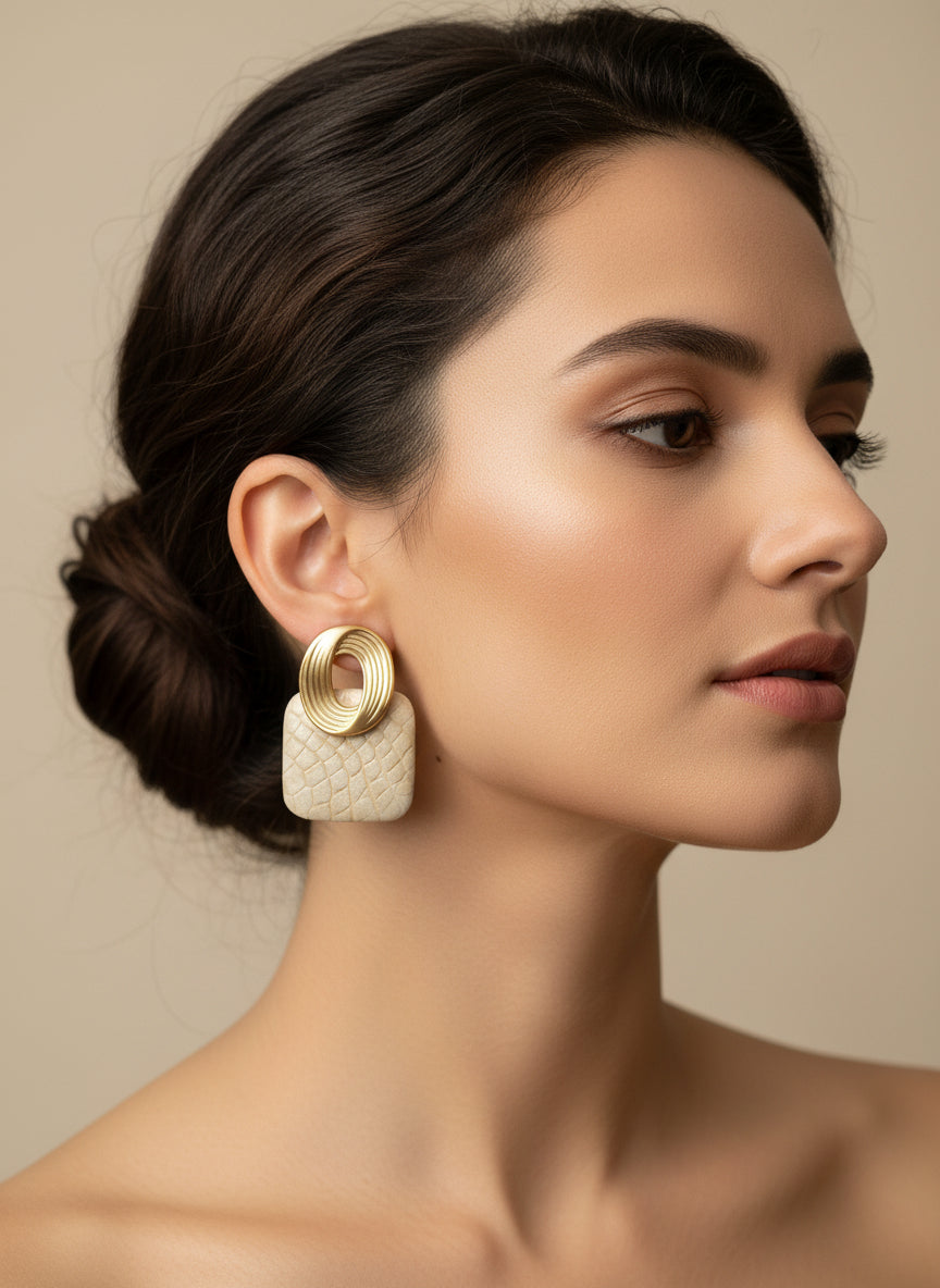 Boucles d’oreilles Thaïs bi matière dorées et ivoire portées par une femme, bijou chic en acier inoxydable longueur 4 cm.