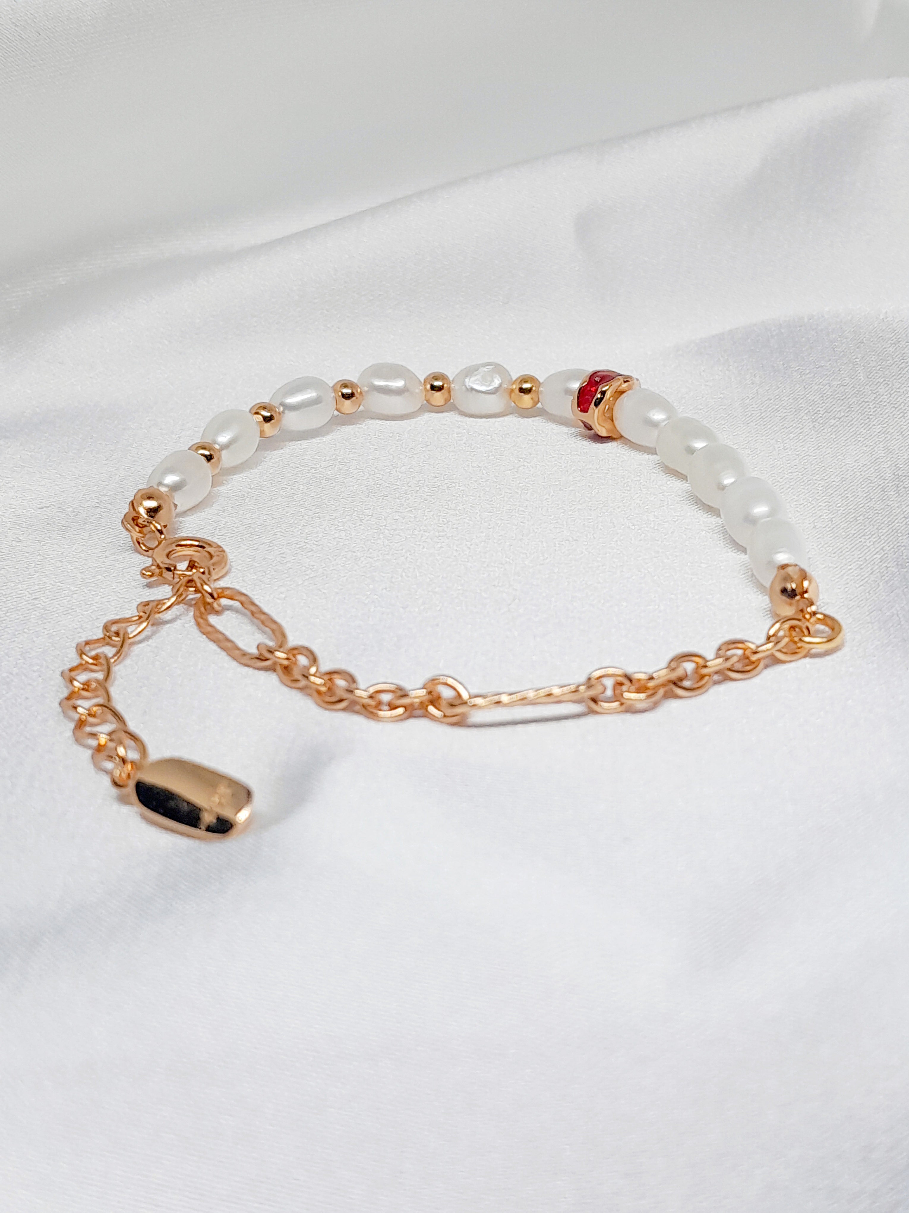 Bracelet Salva en argent sterling 925 plaqué or 18 carats, orné de perles de culture blanches et d’un détail rouge élégant, bijou raffiné Oréa Bijoux.