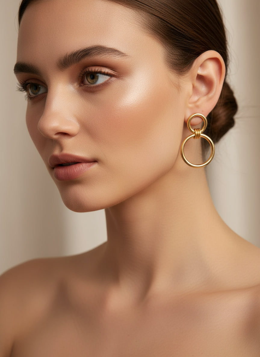 Boucles d’oreilles Énora dorées en acier inoxydable, design à deux anneaux entrelacés, longueur 3 cm, hypoallergéniques et résistantes à l’eau.