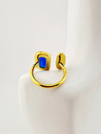 Bague dorée Gina en acier inoxydable avec pierre rectangulaire bleue sur fond neutre