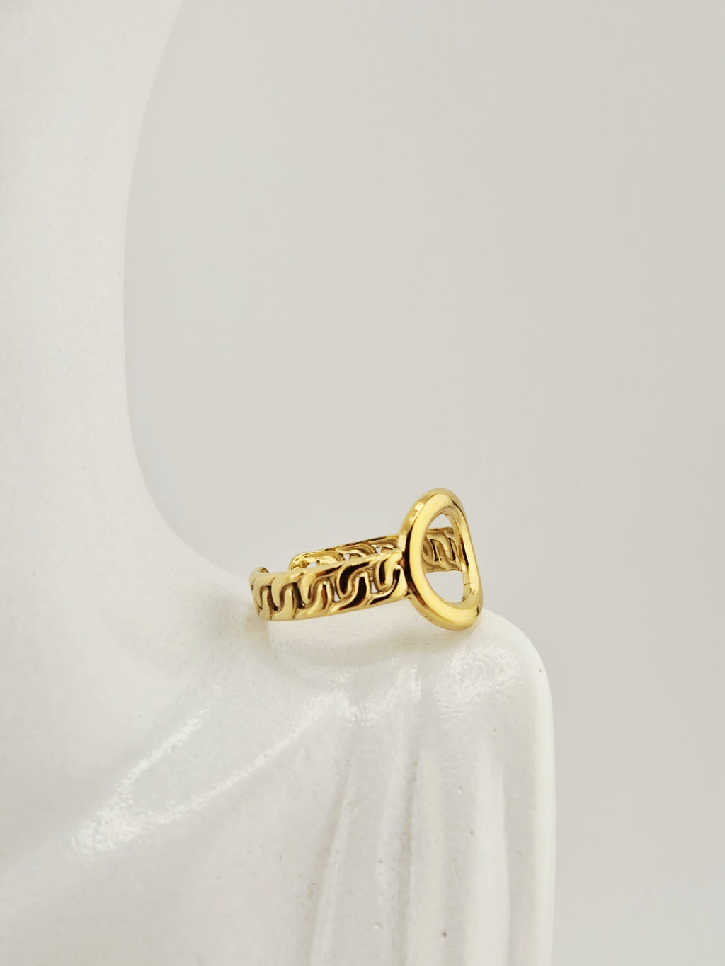 Bague dorée femme avec motif chaîne et cœur ajouré sur fond neutre