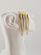 Boucles d’oreilles dorées minimalistes à chaînes pendantes en acier inoxydable, présentées sur un présentoir blanc design.