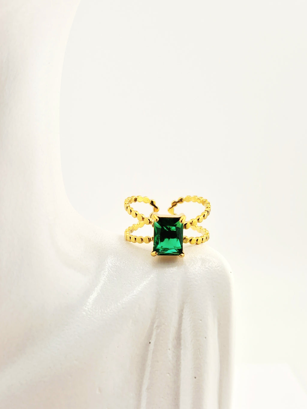 <img src="bague-delta.jpg" alt="Bague Delta dorée avec pierre verte rectangulaire et design torsadé en acier inoxydable">
