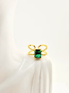 <img src="bague-delta.jpg" alt="Bague Delta dorée avec pierre verte rectangulaire et design torsadé en acier inoxydable">
