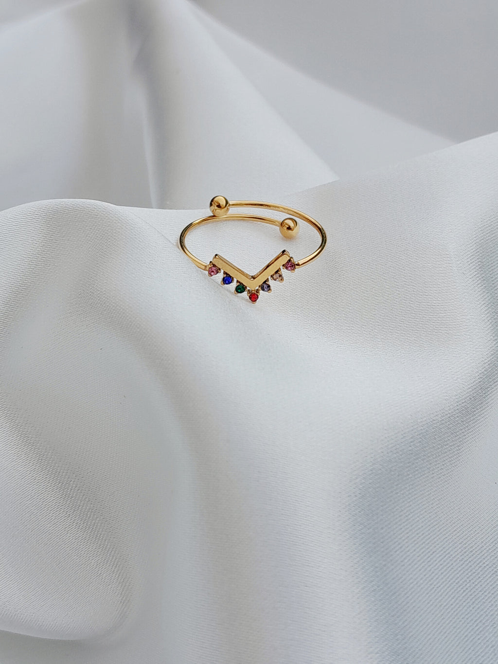 alt="Bague Melina dorée avec pierres colorées en dégradé sur fond blanc"