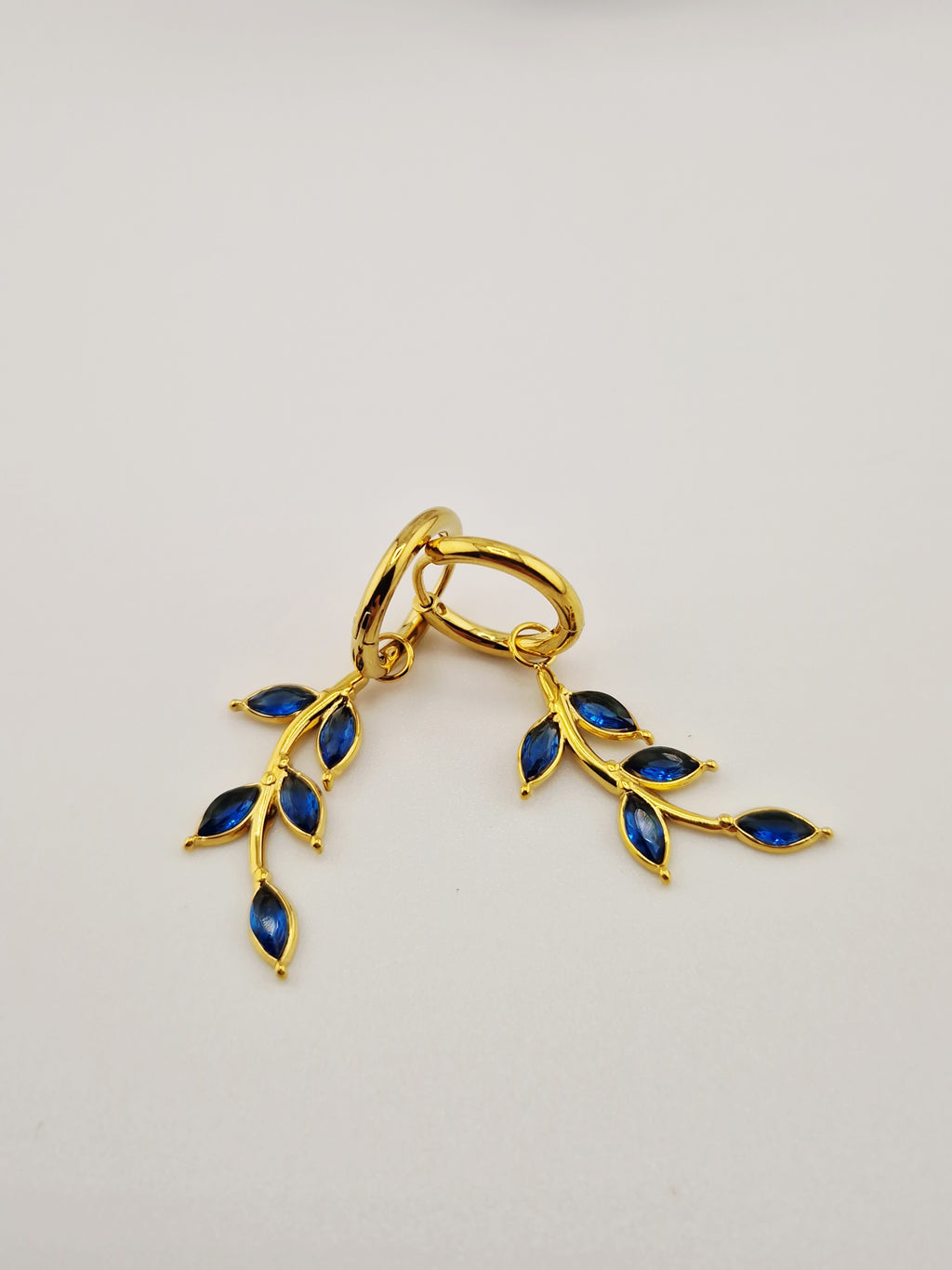 Boucles d’oreilles Éléa en acier inoxydable doré avec pendentif branche et pierres bleues.