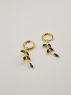 Boucles d’oreilles Éléa en acier inoxydable doré avec pendentif branche et pierres bleues.