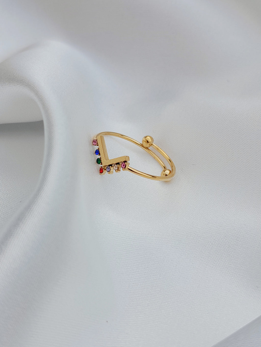 alt="Bague Melina dorée avec pierres colorées en dégradé sur fond blanc"