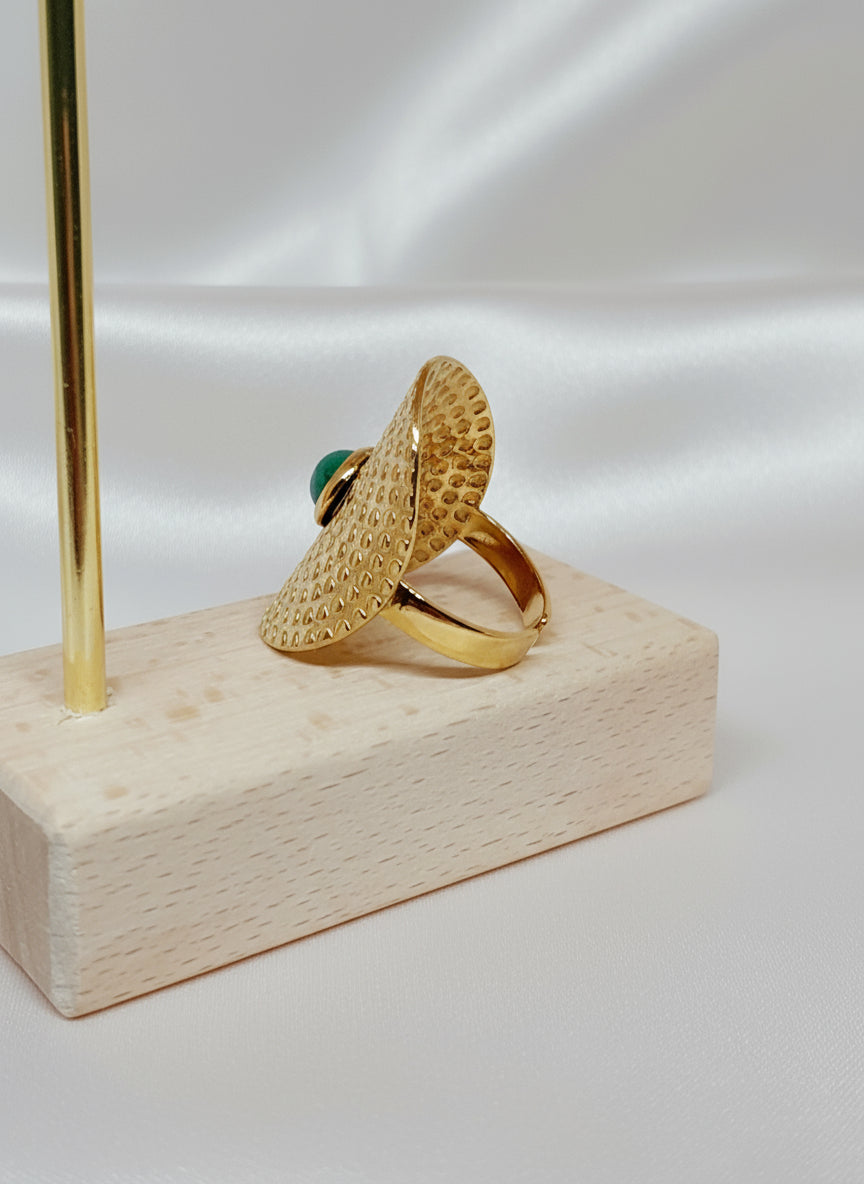 Bague Amal en acier inoxydable doré avec pierre verte sur fond satiné