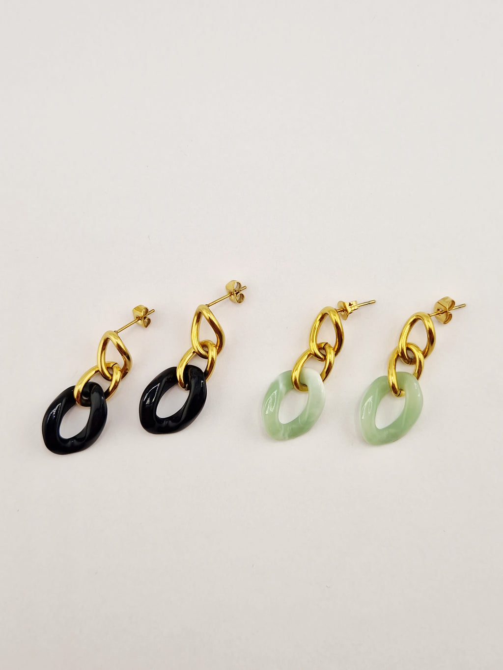Boucles d’oreilles Yumi en acier inoxydable doré avec pendentifs noirs et verts sur fond clair