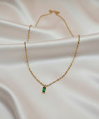 Collier Romy en acier inoxydable doré avec pendentif rectangulaire vert sur fond en satin