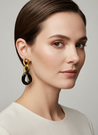 Boucles d’oreilles Yumi en acier inoxydable doré avec pendentifs noirs porté sur fond clair