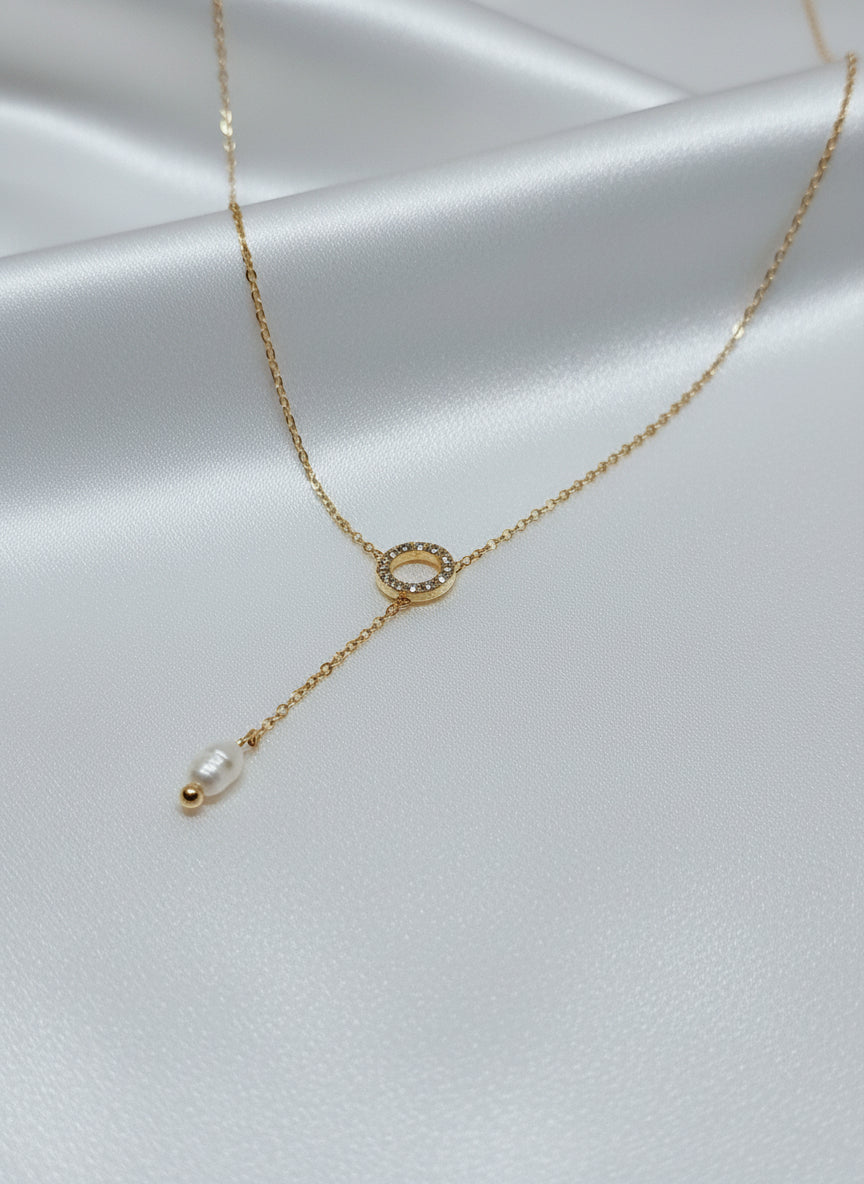 Collier doré femme Aura avec cercle zircon et perle blanche sur fond satiné 