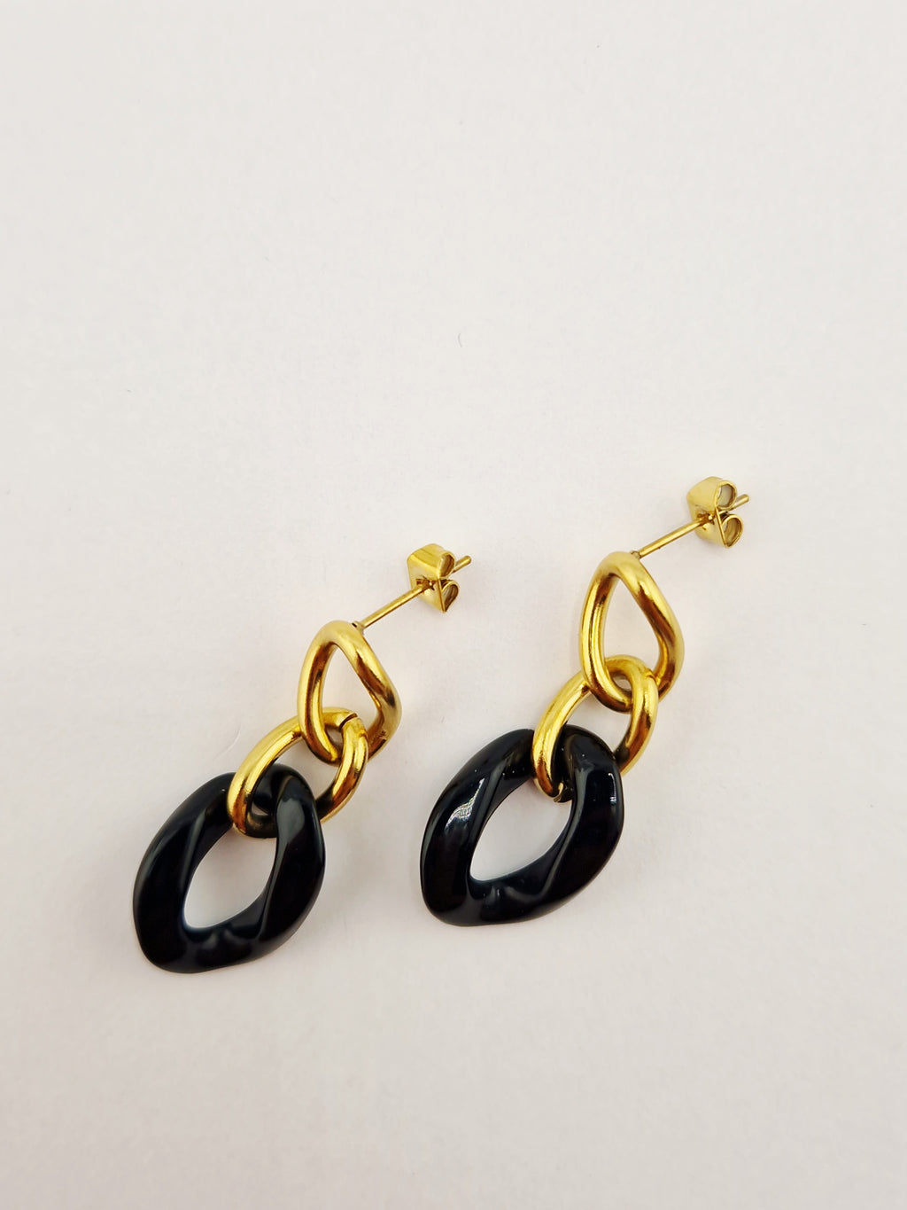 Boucles d’oreilles Yumi en acier inoxydable doré avec pendentifs noirs  sur fond clair