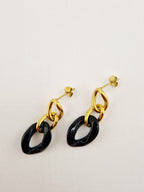 Boucles d’oreilles Yumi en acier inoxydable doré avec pendentifs noirs  sur fond clair