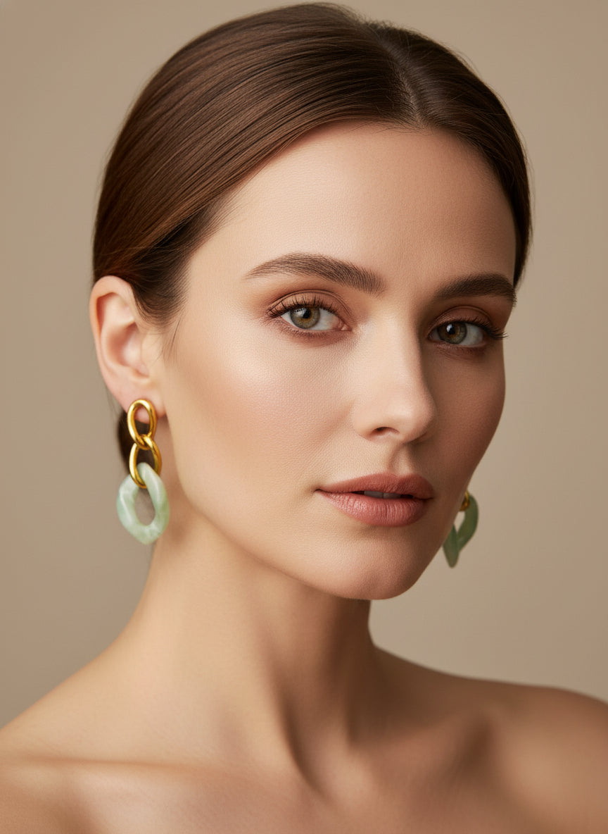 Boucles d’oreilles Yumi en acier inoxydable doré avec pendentifs  verts porté sur fond clair