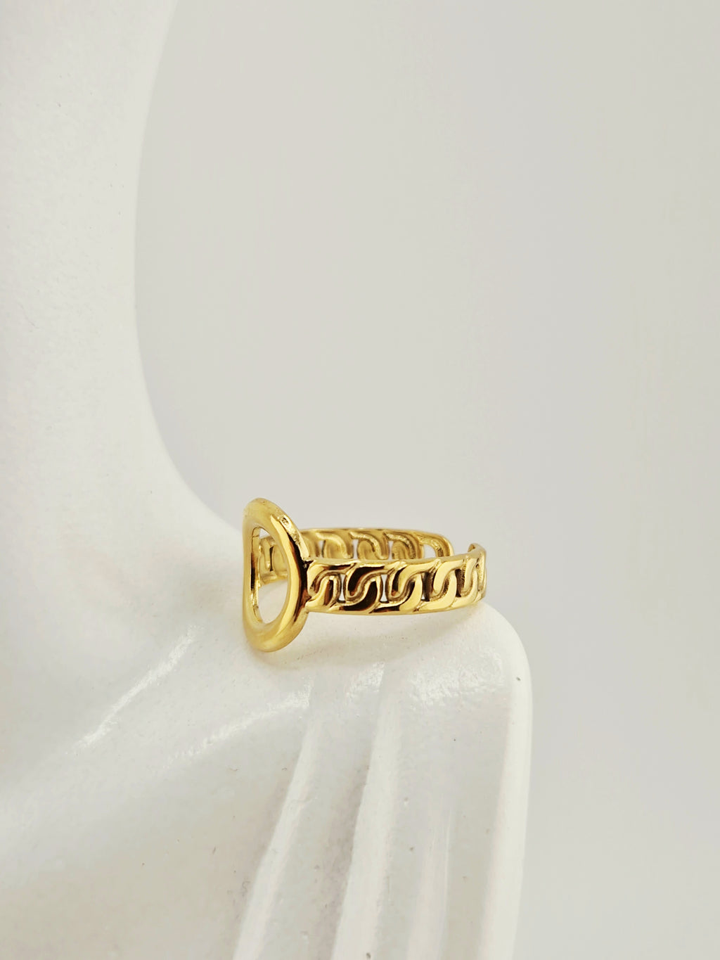 Bague dorée femme avec motif chaîne et cœur ajouré sur fond neutre
